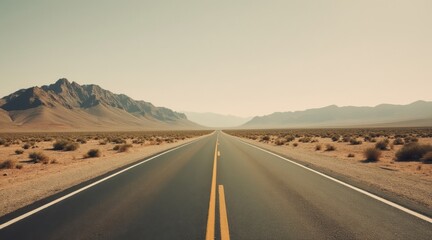 Naklejka premium Empty long straight desert road stretches into vast mountain landscape.