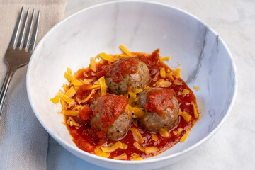 three meat balls in sauce and cheese