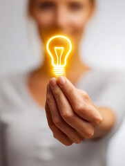Woman holding a glowing light bulb symbol representing creative ideas and innovation with a blurred background for inspiration and brainstorming concepts