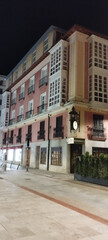 Foto nocturna de un edificio con fachada rosa o salm&oacute;n y galer&iacute;as blancas acristaladas en Burgos