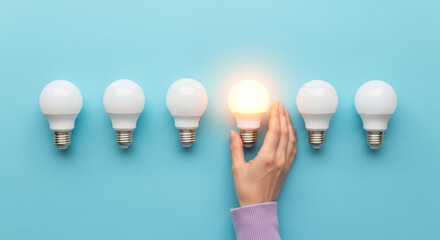 Best job candidate concept with glowing light bulb among unlit bulbs on blue background, standout choice and success symbol