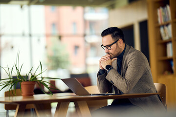 Obraz premium Thoughtful Professional Beside Laptop in Bright Library Office, Deep in Focus and Planning