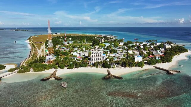 Aerial view of the vibrant Thulusdhoo Island with turquoise waters meeting sandy beaches, contrasted by the island's buildings, Thulusdhoo, North Male Atoll, Maldives.