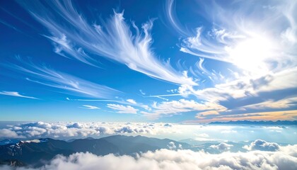 Panoramic view showcasing a vibrant blue sky filled with wispy clouds above mountain peaks. Sunlight streams through the clouds