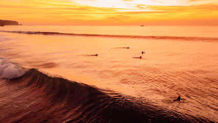 Sunset over ocean waves with surfers and bright sky
