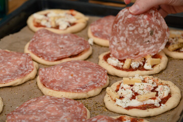 Make mini pepperoni pizzas with salami, mozzarella and tomato sauce, a party snack