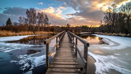 Wooden bridge over river at sunset.