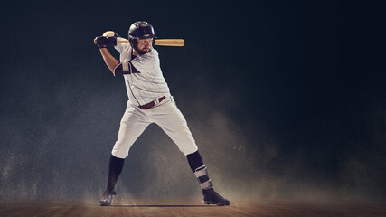 Baseball batter in ready stance holding bat before swing on dusty field. Concept of anticipation,...