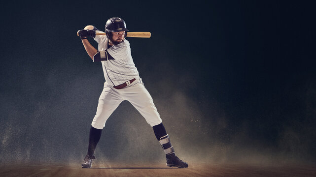 Baseball batter in ready stance holding bat before swing on dusty field. Concept of anticipation, athletic discipline, professional performance for sportswear marketing and coaching materials.