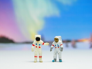 Mini toy of action figure at table with blurred background. Miniature photography concept design. Minifigure of Astronaut character landing at new planet conceptual. Exploring space with Aurora view.