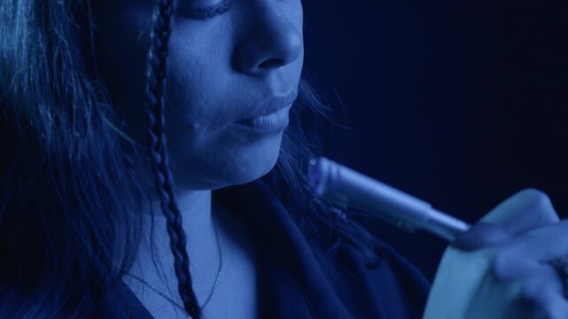 A woman pens notes in a moody blue close-up shot. The focus on her hand reveals intricate penmanship under low, dramatic lighting, creating an intimate and thoughtful atmosphere.