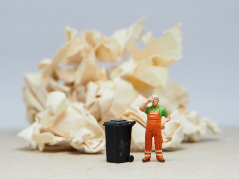 Mini toy of action figure at outdoor with blurred background. Miniature photography concept design. Minifigure of people character with garbage truck at urban city.