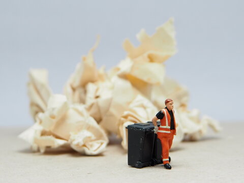 Mini toy of action figure at outdoor with blurred background. Miniature photography concept design. Minifigure of people character with garbage truck at urban city.