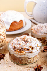 Delicious layered cinnamon roll overnight oatmeal. Tasty breakfast overnight oats in jar, tasty comfort morning food, sweet healthy snack with greek yogurt topping and sprinkle of cinnamon bun spice 