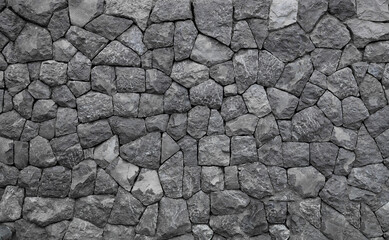 gray stone rock wall features a smooth. wall surface is composed of natural grey stones, carefully arranged to create uniform. grey stoned wall, decorative wall made of large stones pattern background