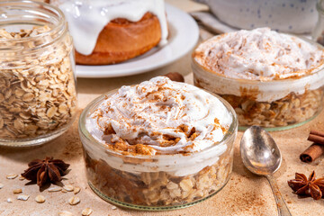 Delicious layered cinnamon roll overnight oatmeal. Tasty breakfast overnight oats in jar, tasty comfort morning food, sweet healthy snack with greek yogurt topping and sprinkle of cinnamon bun spice 