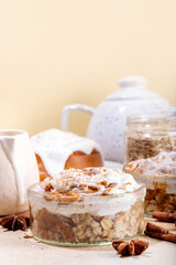 Delicious layered cinnamon roll overnight oatmeal. Tasty breakfast overnight oats in jar, tasty comfort morning food, sweet healthy snack with greek yogurt topping and sprinkle of cinnamon bun spice 