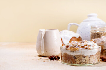 Delicious layered cinnamon roll overnight oatmeal. Tasty breakfast overnight oats in jar, tasty comfort morning food, sweet healthy snack with greek yogurt topping and sprinkle of cinnamon bun spice 