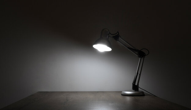 electrical illuminated of desk lamp. empty brown wooden classic table lamp shining on a clean white light blue wall ready for work at evening night. mock up mockup mock-up template blank