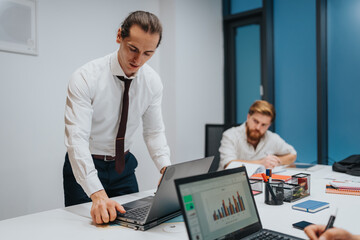 Professional team in a modern office discusses charts and notes while one presenter demonstrates...