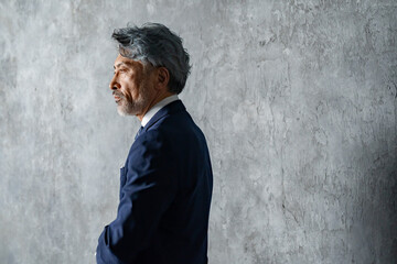 グレー背景の前でスーツ姿の男性
