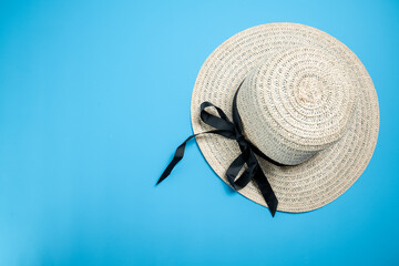 Straw hat with a black ribbon on a blue background. Concept of travel, summer, or vacation