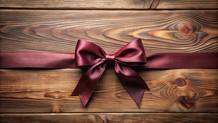 Fototapeta premium Elegant maroon satin ribbon tied in a perfect bow, adorning rustic wooden planks.