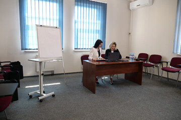 Women during a business presentation point to charts on the flipchart while discussing strategy.