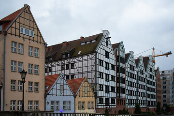 Traditional half-timbered buildings in the historic Old Town of Gdańsk, Poland, with classic European architecture and red tile roofs under a cloudy sky