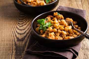 Cauliflower and chickpeas curry salad on wooden table, healthy vegan food