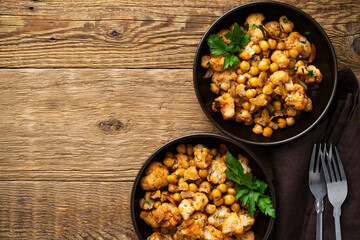 Cauliflower and chickpeas curry salad on wooden table, healthy vegan food