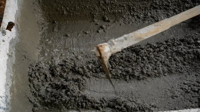 Close-up of Construction Workers Mixing Cement and Sand in a Plastic Tub, Highlighting Manual Labor and Building Foundation Preparation.