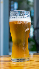 beer in a glass on a brown table with a blurry background