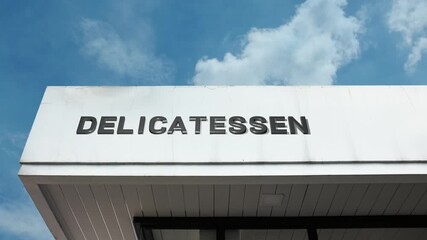 Delicatessen word sign displayed on building facade with clear blue sky, highlighting a specialty food shop, gourmet store, or culinary business in daylight.