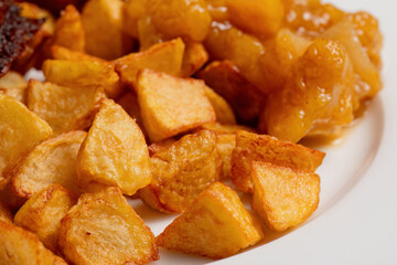 Golden roasted potatoes on white plate
