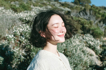 Peaceful portraits of a smiling woman enjoying the breeze in natural seaside light