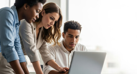 Diverse professionals collaborating intensely on laptop in bright office
