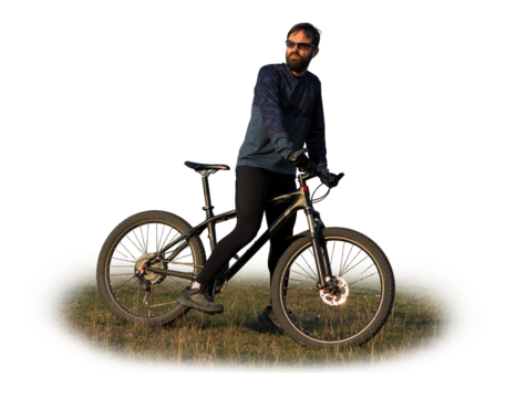 Cyclist in shorts and jersey on a modern carbon hardtail bike with an air suspension fork standing on a cliff against the background of fresh green spring forest