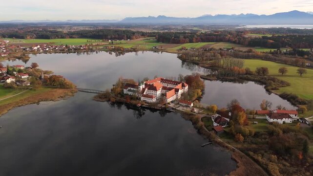 Autumn aerial panorama of Kloster Seeon Monastery on a small peninsula in Lake Seeon, surrounded by forests and reflections, Upper Bavaria, Germany. Luftaufnahme Kloster Seeon in Seeon-Seebruck. 