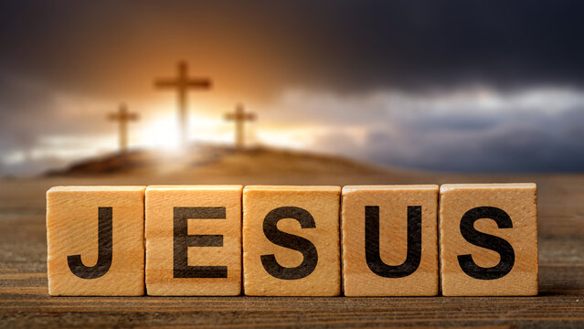 Row of wooden cubes with text of Jesus on the table with a Christian cross on the hill with dark dramatic sky background. Concept of Christianity, religious, faith, Jesus, or belief - Powered by Adobe