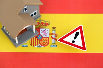 Residential house with alert sign on Spanish flag close up. Concept of Squatting in Spain. Okupas problem