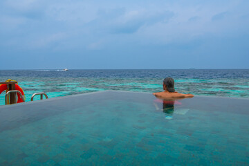 Tranquil closeup calm sea water waves with palm trees. Man tourist posing, Tropical island beach landscape exotic shore coast. Summer vacation, holiday amazing nature. Relax paradise, Maldives.