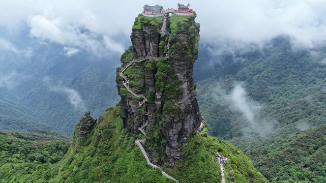 Aerial view of the Fanjingshan temple sitting atop a lush green mountain peak surrounded by clouds, Fanjingshan, Guizhou, China.