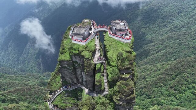 Aerial view of the majestic Fanjingshan temples perched atop a verdant, cloud-kissed peak with winding staircases, Fanjingshan, Guizhou, China.