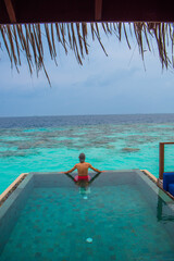 Tranquil closeup calm sea water waves with palm trees. Man tourist posing, Tropical island beach landscape exotic shore coast. Summer vacation, holiday amazing nature. Relax paradise, Maldives.