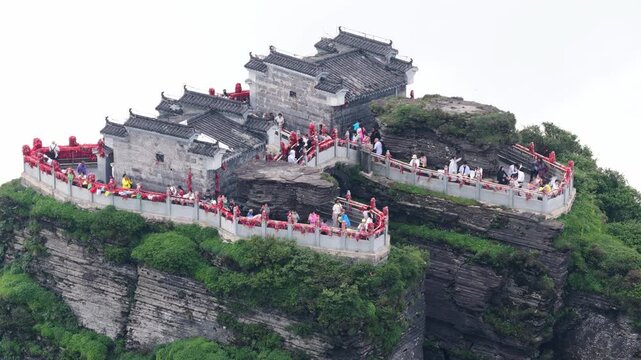 Aerial view of the Fanjingshan Temple perched atop a mountain, its grey stone contrasting with the lush green vegetation, Fanjingshan, Guizhou, China.
