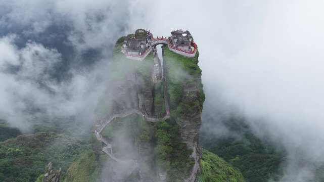 Aerial view of the majestic Fanjingshan mountain peak piercing the clouds, with winding steps leading to the temple, Fanjingshan, Guizhou, China.