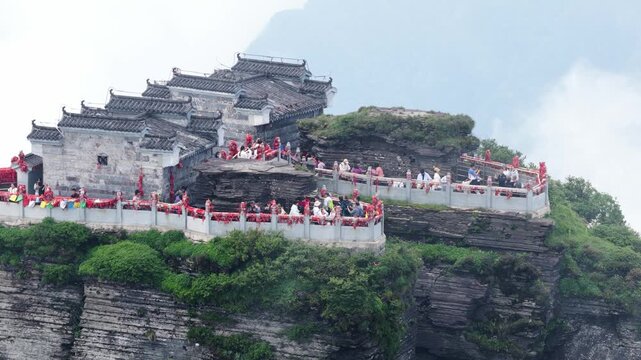 Aerial view of a temple atop a mountain with people, revealing the textures of the stone and green foliage, Fanjingshan, China.
