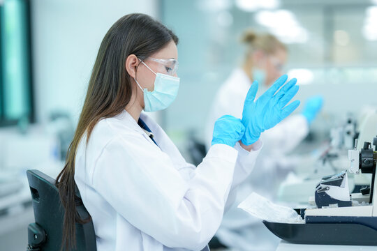 A team of female medical researchers works in a bright, modern hospital laboratory. They are focused on preparing tissue samples for diagnostic testing and scientific study.