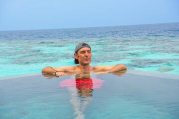 Tranquil closeup calm sea water waves with palm trees. Man tourist posing, Tropical island beach landscape exotic shore coast. Summer vacation, holiday amazing nature. Relax paradise, Maldives.